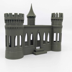 May include: A grey 3D printed castle model with two towers and a pointed roof. The castle has a central doorway and several windows.