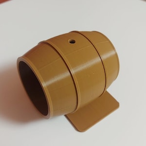 May include: A brown wooden barrel with a small hole in the top. The barrel is sitting on a small brown base.