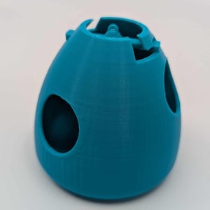 May include: A teal blue 3D printed model of a spacecraft with a hinged hatch and multiple openings.