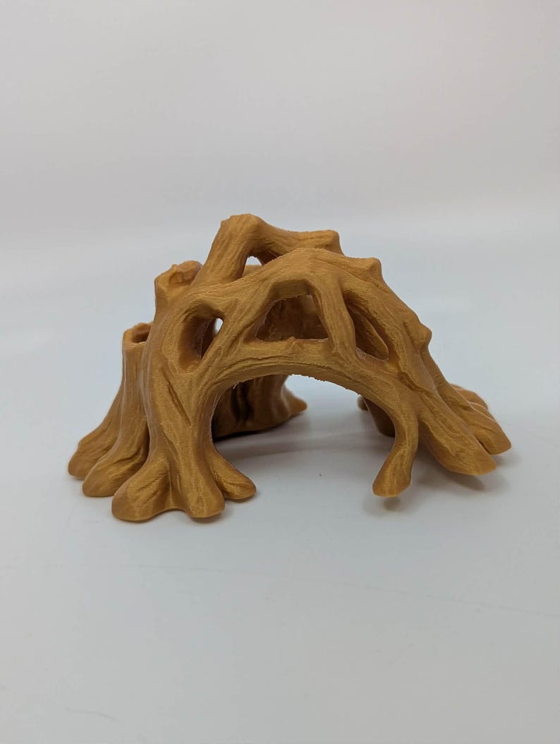 May include: A detailed, tan-colored miniature tree stump with an arched opening. The sculpture features a textured surface, mimicking the look of tree bark, and is designed with multiple openings and a rounded base.