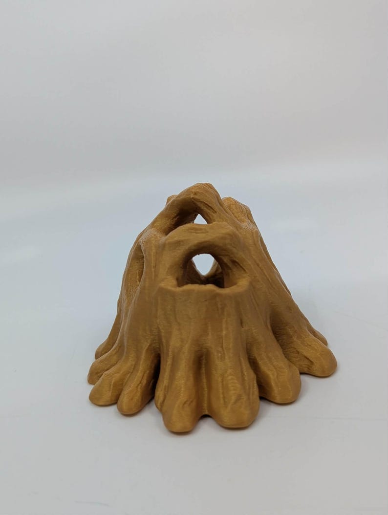 May include: A 3D-printed, tan-colored tree stump with multiple openings. The stump has a textured surface and a naturalistic design, suitable for decorative purposes or as a small animal habitat.