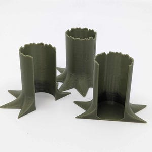 May include: Three olive green tree stump-shaped holders. Each has a cylindrical body with a jagged top edge, resembling a cut tree. The bases are flared out to resemble roots. These holders are likely for pens, pencils, or small plants.