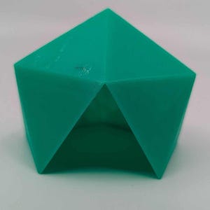May include: A teal green geometric shape with a hollow center. The shape is a three-dimensional object with multiple sides.