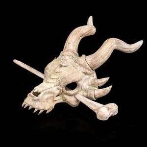 May include: A white dragon skull with horns and teeth, made of resin, with a bone-like texture. The skull is mounted on a wooden stick.
