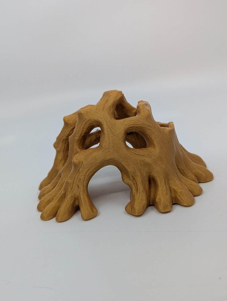 May include: A 3D-printed, tan-colored tree stump with multiple openings and a textured surface. The design features a hollowed-out center and detailed, organic shapes, suitable for decorative purposes or as a small animal habitat.