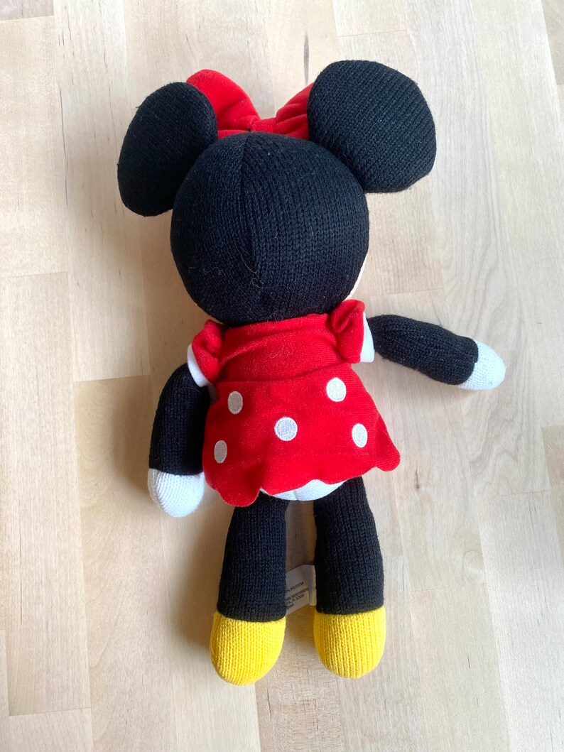 May include: A black and red knitted Minnie Mouse plush toy with white polka dots on her red dress. She has large black ears and a red bow.