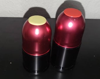 May include: Two red metal canisters with black lids. The canister on the left has a light yellow top, and the canister on the right has a red top.
