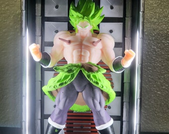 May include: A green and black action figure of a character with spiky green hair, a muscular build, and a green and black outfit. The figure is posed in a fighting stance and is displayed in a black frame with white lights.
