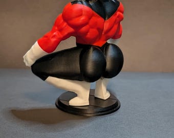 May include: A 3D-printed figurine of Jiren from Dragon Ball Super. The figure is in a squatting pose, with a bald head, red upper body, black pants, and white accents. It stands on a black circular base.