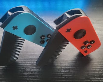 May include: Two Nintendo Switch Joy-Con controllers, one blue and one red, are modified to look like combs. The controllers are lying on a black wooden surface.