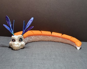 May include: A white and orange sushi-shaped dragon with blue and purple wings. The dragon is made of plastic and is a toy.