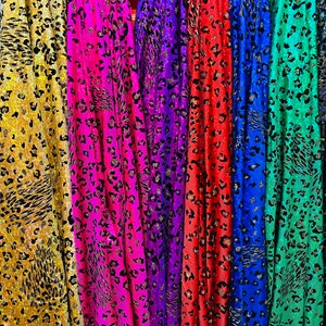 May include: A collection of eight fabric swatches with a leopard print pattern. The fabrics are in various colors, including white, yellow, pink, purple, blue, red, green, and black.