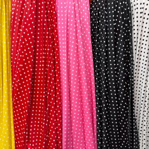 May include: Fabric panels in yellow, red, pink, black, and white, each patterned with white polka dots. The fabric is draped, showing soft folds. The image presents a variety of colours and textures, suitable for clothing or home decor.