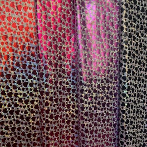 May include: Three fabric swatches with a holographic heart pattern. The swatches are red, pink, and black.