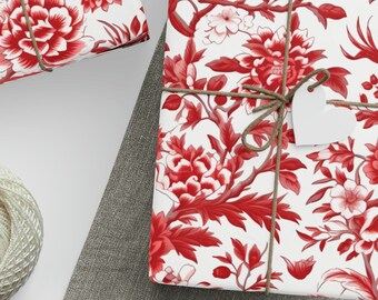 May include: Several gift-wrapped presents featuring a red floral design on white paper, tied with twine and blank tags. A ball of twine, scissors, and extra tags are also present, indicating a focus on gift wrapping and presentation.