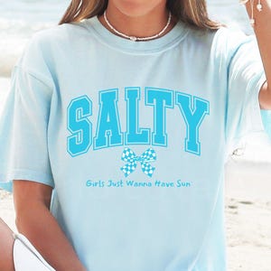 Camisa de praia Salty Coquette, camiseta azul universitária com letras e laço xadrez, camiseta estética feminina estilo cowgirl costeira, cores confortáveis para o oceano