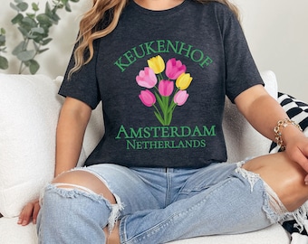 May include: A dark grey t-shirt with a green graphic of a bouquet of pink and yellow tulips. The text "KEUKENHOF AMSTERDAM NETHERLANDS" is printed on the shirt.