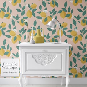 Peut inclure: Une table blanche avec un panneau avant décoratif et des pieds incurvés. Le fond est un papier peint avec un motif de citrons jaunes, de feuilles vertes et de fleurs blanches sur un fond rose. Une lampe de bureau blanche, un vase jaune et d'autres objets décoratifs sont sur la table.