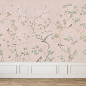 Op de afbeelding: Een roze behang met een bloemen- en vogelontwerp. Het behang toont delicate takken met witte bloemen en groene bladeren, samen met kleine vogels in tinten blauw en bruin.