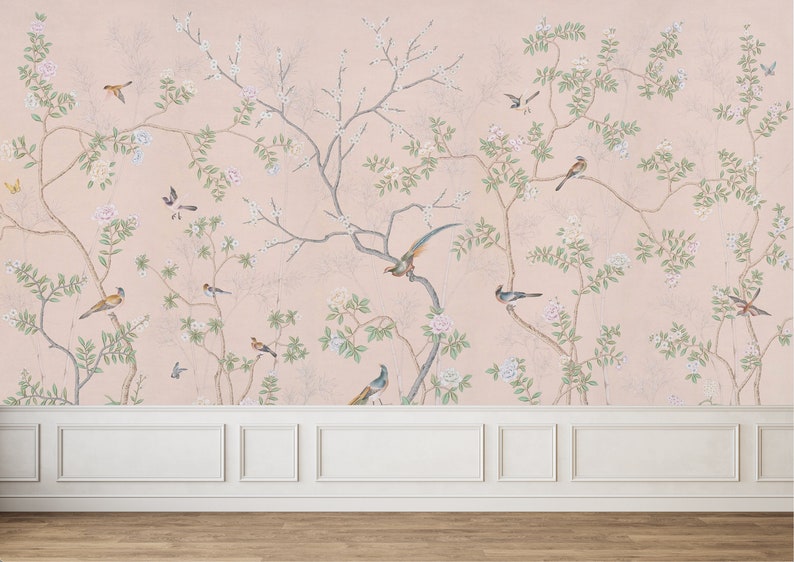 Op de afbeelding: Een roze behang met een bloemen- en vogelontwerp. Het behang toont delicate takken met witte bloemen en groene bladeren, samen met kleine vogels in tinten blauw en bruin.