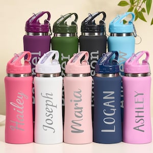 May include: A collection of personalized water bottles in various colors, including pink, white, and blue. Each bottle has a flip-top lid and a name printed on the side. The bottles are designed for hydration and are suitable for everyday use.