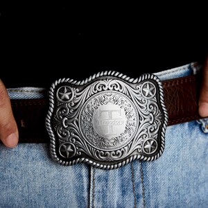 May include: A silver belt buckle with an ornate design and a central circle featuring the letter "T" and the name "Theodore".