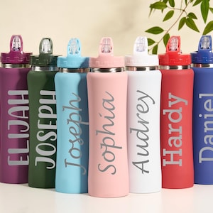 May include: A collection of personalized water bottles in various colors, including purple, green, blue, pink, white, red, and blue. Each bottle features a name in a stylish font. The bottles have a sleek design with a flip-top lid.