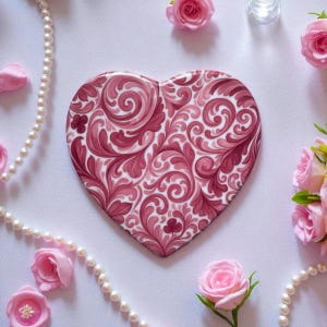 Può includere: Una piastrella decorativa a forma di cuore con un motivo floreale a spirale nei toni del rosa e del bordeaux. La piastrella è circondata da rose rosa e una collana di perle, creando un'estetica romantica ed elegante. La piastrella misura circa 15 cm.