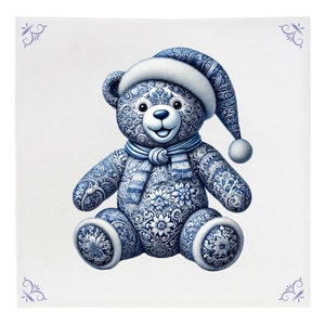 May include: A blue and white porcelain teddy bear wearing a white Santa hat and a blue and white scarf. The bear is sitting on a white background.