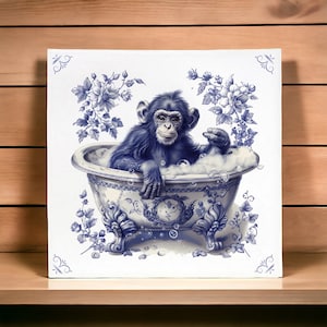 Puede incluir: Una bañera de porcelana azul y blanca con un chimpancé sentado en ella. El chimpancé está sosteniendo una pastilla de jabón y tiene una expresión juguetona en su rostro. La bañera está decorada con diseños florales.