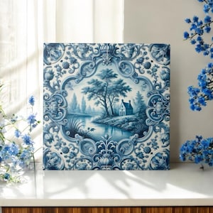 Op de afbeelding: Een blauwe en witte keramische tegel met een decoratieve rand en een scène van een huis aan een rivier met bomen.
