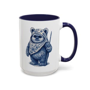 Op de afbeelding: Witte keramische mok met marineblauw interieur en handvat. De mok heeft een blauwe illustratie van een Ewok-personage met een hoofdbedekking en een staf. Het ontwerp is gedetailleerd en grillig.