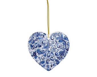 Op de afbeelding: Een blauwe en witte keramische hartvormige ornament met een bloemenpatroon. De ornament hangt aan een gouden touwtje.