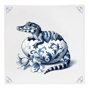May include: A blue and white porcelain egg with a blue and white alligator hatching out of it. The egg is decorated with a floral pattern. There are two white lilies on the left side of the egg.