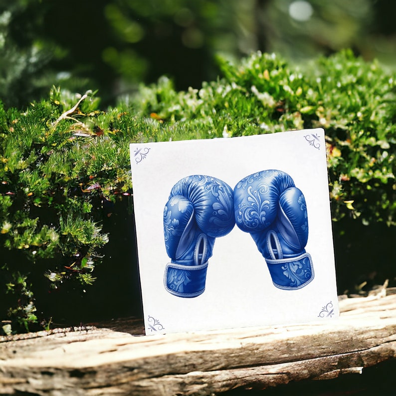 K&ouml;nnte beinhalten: Zwei blaue Boxhandschuhe mit einem Blumenmuster. Die Handschuhe sind einander zugewandt, die Schn&uuml;rsenkel sind gebunden.