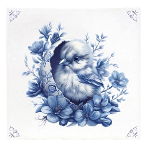 以下が含まれることがあります： 青と白のセラミックタイル。青いひよこが割れた卵から出てきて、青い花に囲まれている。