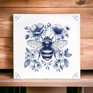 May include: A blue and white illustration of a bee surrounded by flowers. The bee is in the centre of the image and has a fuzzy body and wings. The flowers are arranged around the bee and have delicate petals.