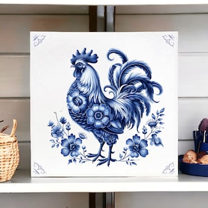 Puede incluir: Un azulejo de cerámica azul y blanco con un gallo con un diseño floral. El gallo está de pie en una rama con flores y hojas.