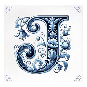 Op de afbeelding: Een blauwe en witte decoratieve letter J met bloemmotieven. De letter is in vintage stijl en is omringd door bloemen en bladeren.