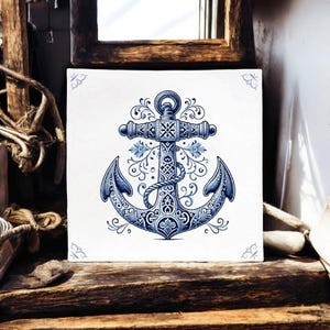 Puede incluir: Un azulejo de cerámica azul y blanco con un diseño de ancla intrincado. El ancla está rodeada de patrones florales y tiene un detalle de cuerda.
