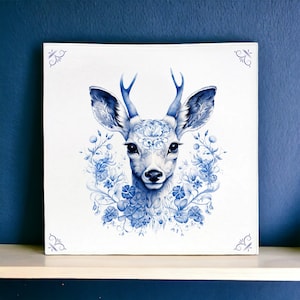 Può includere: Uno sfondo bianco con un'illustrazione di cervo blu e bianco. Il cervo ha un disegno floreale sulla testa e sul corpo. Il cervo è circondato da fiori blu e bianchi.