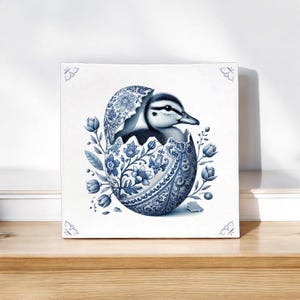 May include: A blue and white porcelain egg with a duckling inside. The egg is decorated with floral patterns and the duckling is looking to the right.