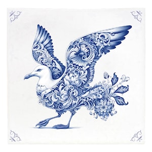 Op de afbeelding: Een blauwe en witte keramische tegel met een gedetailleerde illustratie van een meeuw in vlucht. Het lichaam van de meeuw is gevuld met ingewikkelde bloemmotieven en spiralen.