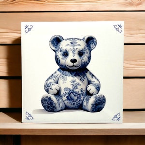 May include: A blue and white porcelain teddy bear with a floral pattern. The bear is sitting on a white background.