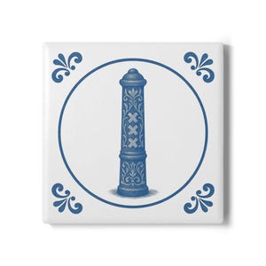 Op de afbeelding: Vierkante witte tegel met een blauwe illustratie van een pilaar met het wapen van Amsterdam. De pilaar is omcirkeld door een blauwe cirkel en decoratieve hoekaccenten. Het ontwerp doet denken aan traditioneel Delfts blauw.