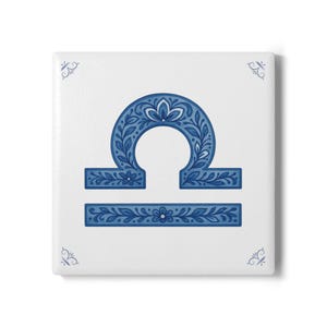 Puede incluir: Azulejo blanco cuadrado con el símbolo del zodiaco Libra azul. El símbolo está decorado con patrones florales y de hojas. Acentos florales azules decorativos en las esquinas completan el diseño. Un artículo decorativo para entusiastas de la astrología.