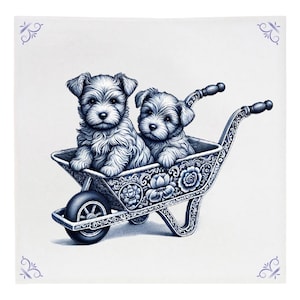 Puede incluir: Dos cachorros blancos se sientan en una carretilla adornada en azul y blanco. La carretilla tiene un diseño floral y los cachorros miran al espectador.