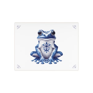 May include: A blue and white frog with a floral design on its chest. The frog is sitting on a white background.