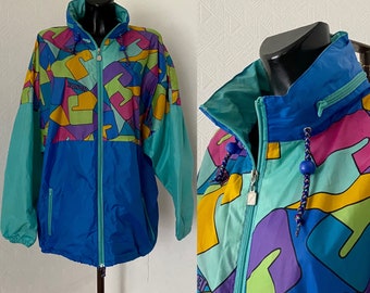 Può includere: Giacca a vento vintage con un vivace design a blocchi di colore. La giacca presenta un collo alto, una cerniera intera e un cappuccio con coulisse. La combinazione di colori include forme geometriche blu, verde acqua, viola, gialle e verdi. La giacca è esposta su un manichino nero.