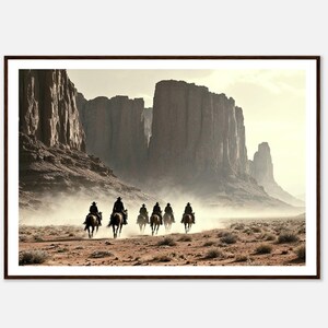 May include: A framed photograph of a group of six cowboys riding horses through a desert canyon. The cowboys are silhouetted against the bright light of the setting sun. The canyon walls are tall and rocky, and the desert floor is covered in sand and dust.